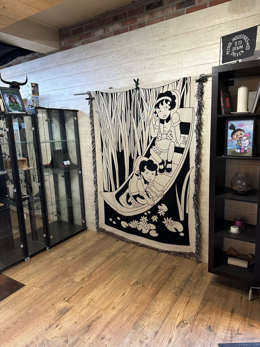 Shoekids woven blanket hanging as a tapestry on a tattoo studio wall